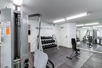 A gym with weights and cardio equipment and a sign that says trust the process